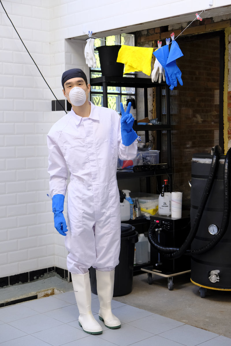 Tim standing by brewing equipment wearing brewing outfit in the brewery.