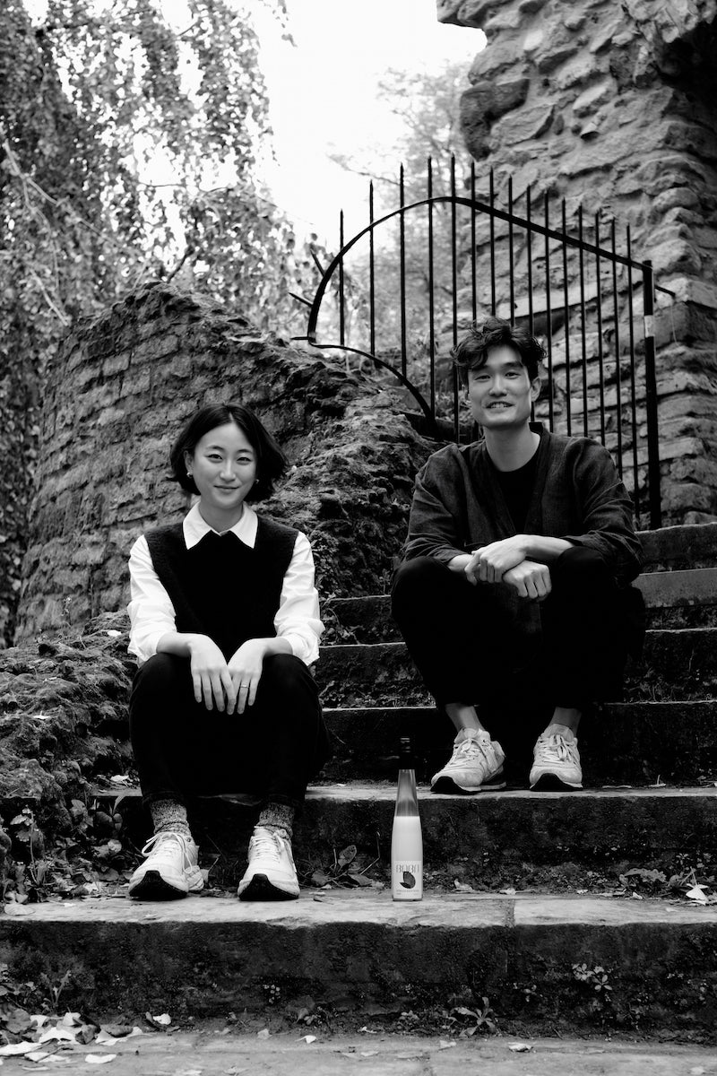 Tim and Yeasle sitting on stairs outside with Babo Makgeolli placed between them.